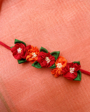 Red orange handcrafted fabric gajra hairtie close-up with floral fabric work