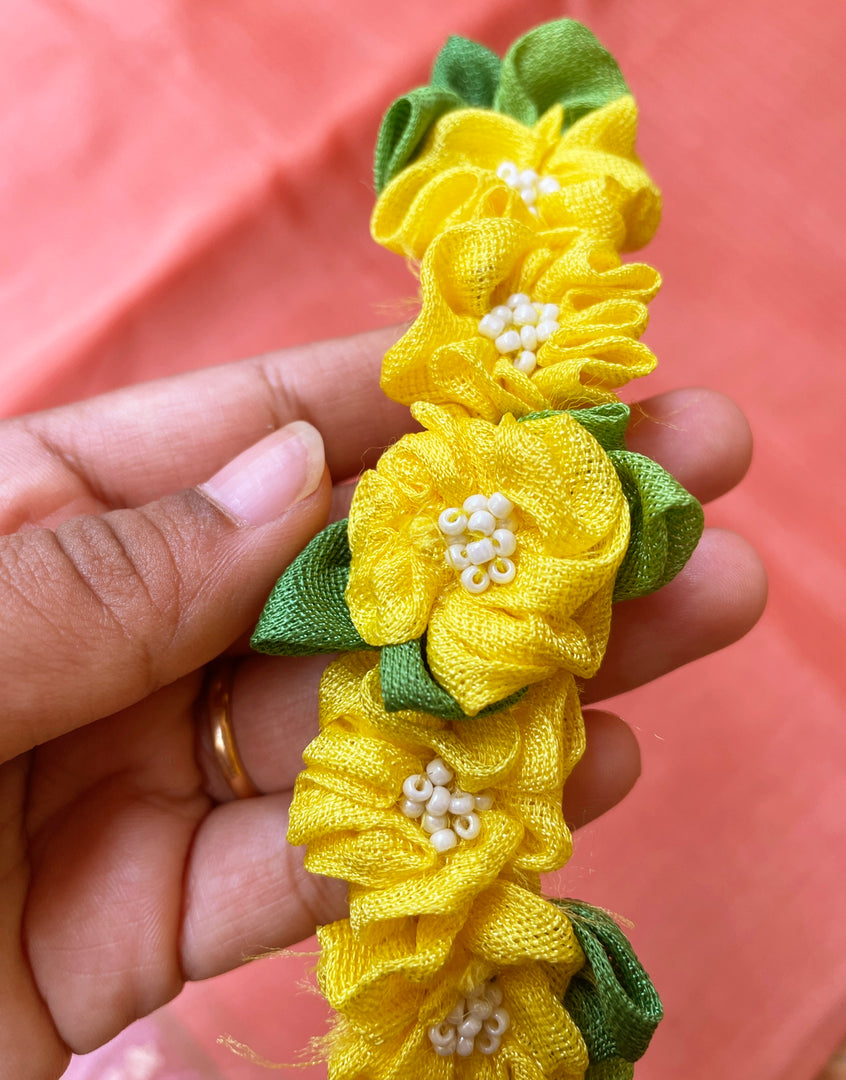 Lemon yellow handcrafted fabric gajra hairtie close-up showing fabric flowers